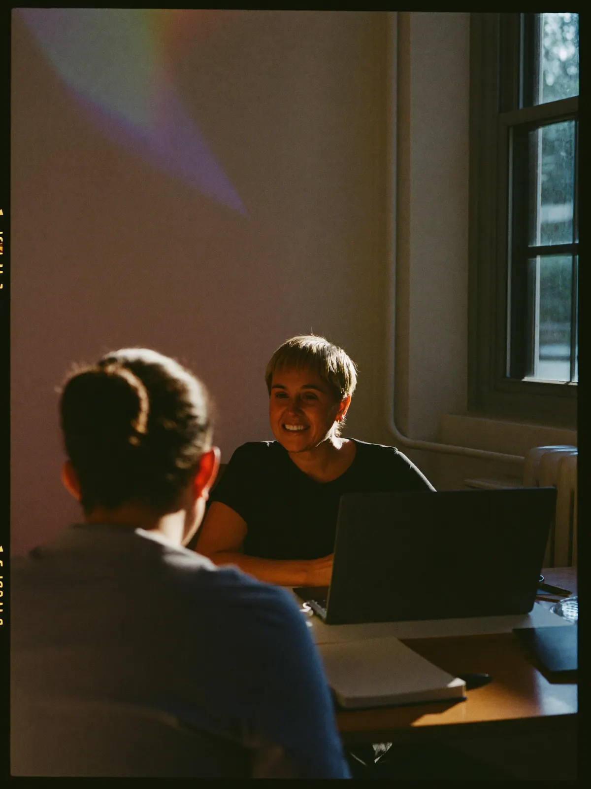 An interviewer smiling across the table at a candidate seen from behind