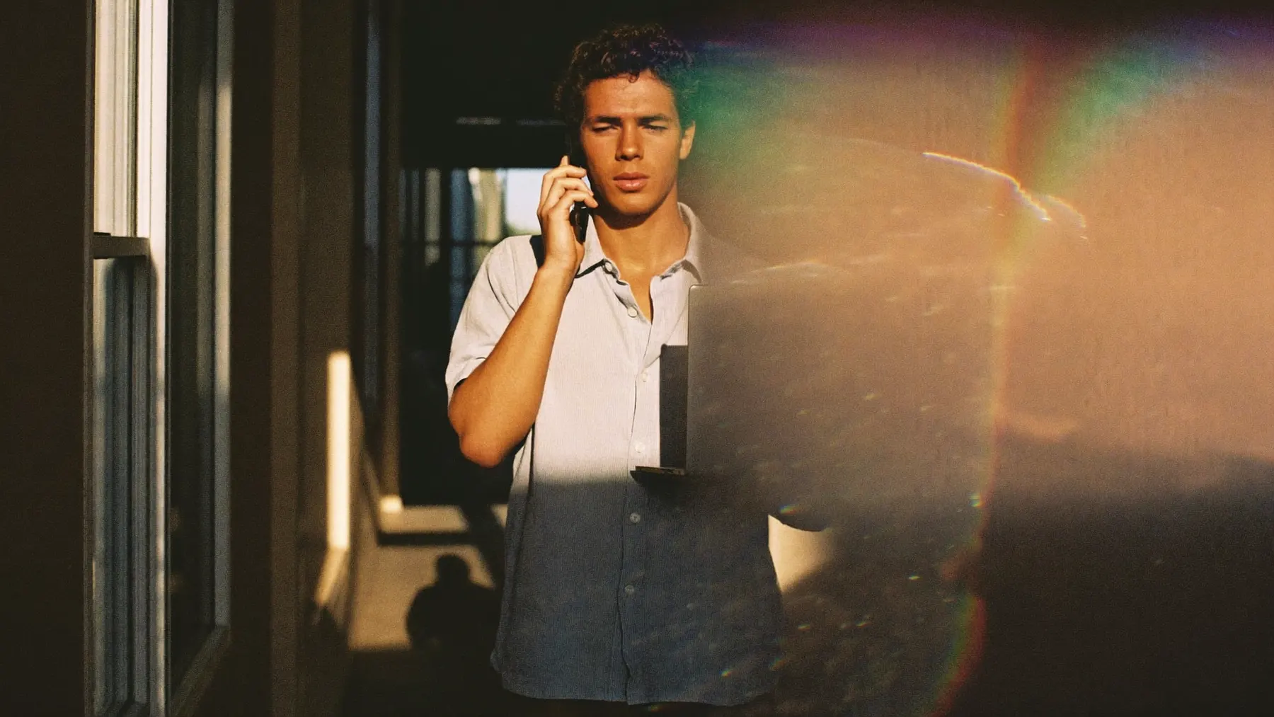 A man in a sunlit corridor talking a thought through on his phone