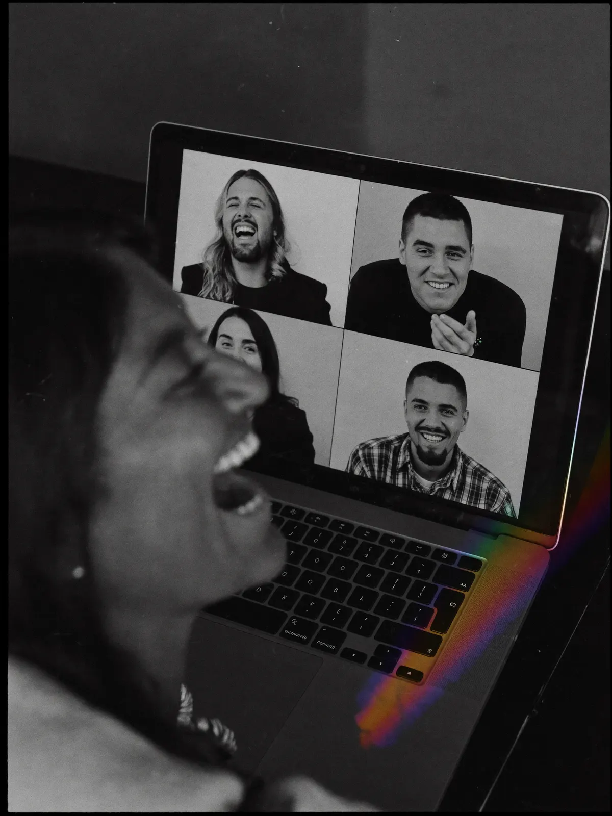 A woman laughing on a video call, her screen a grid of four faces and no bot among them