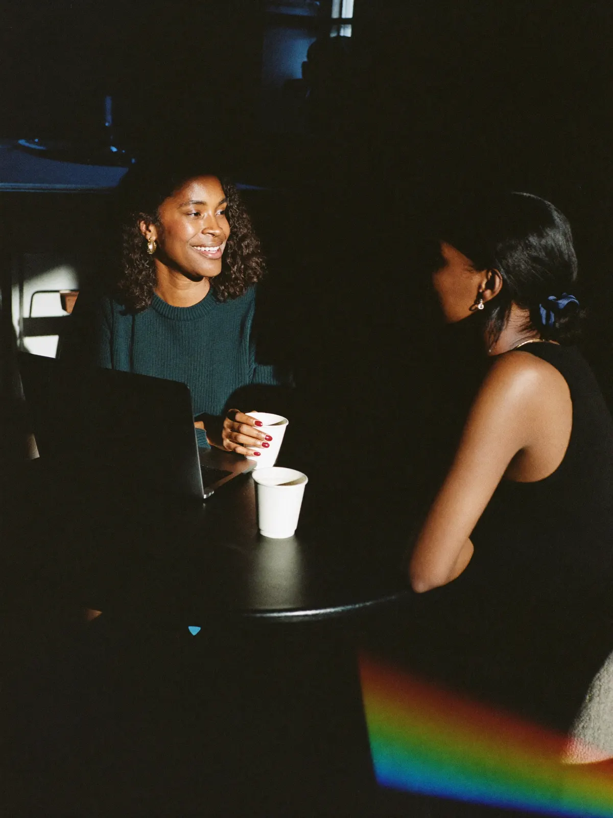 Two colleagues talking over coffee at a small round table