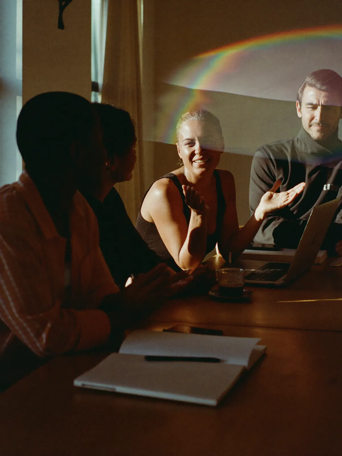 A small team around a meeting table, one person talking with open hands